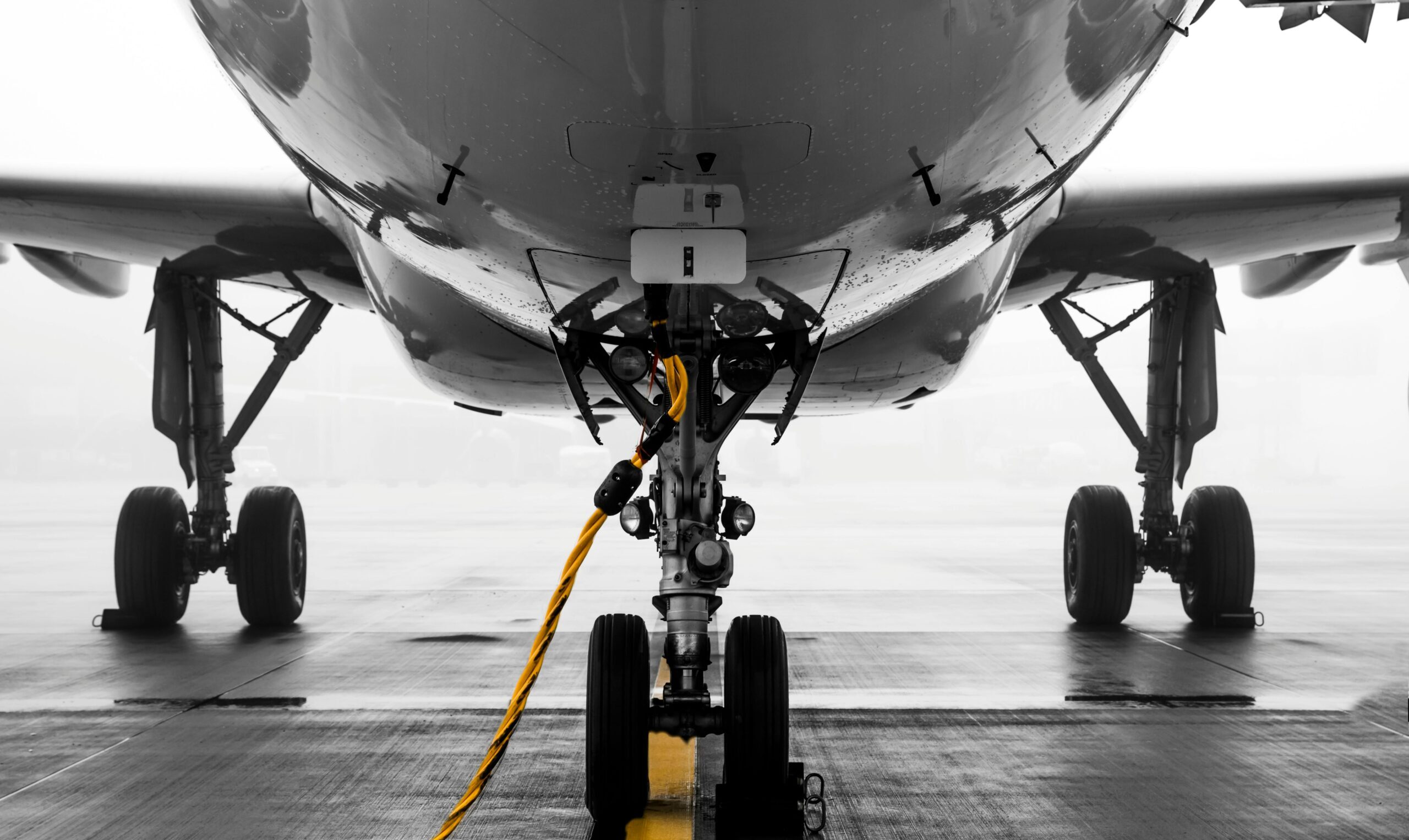 Close-up of a modern aircraft on a misty runway at Zürich Airport, highlighting the landing gear and foggy ambiance.