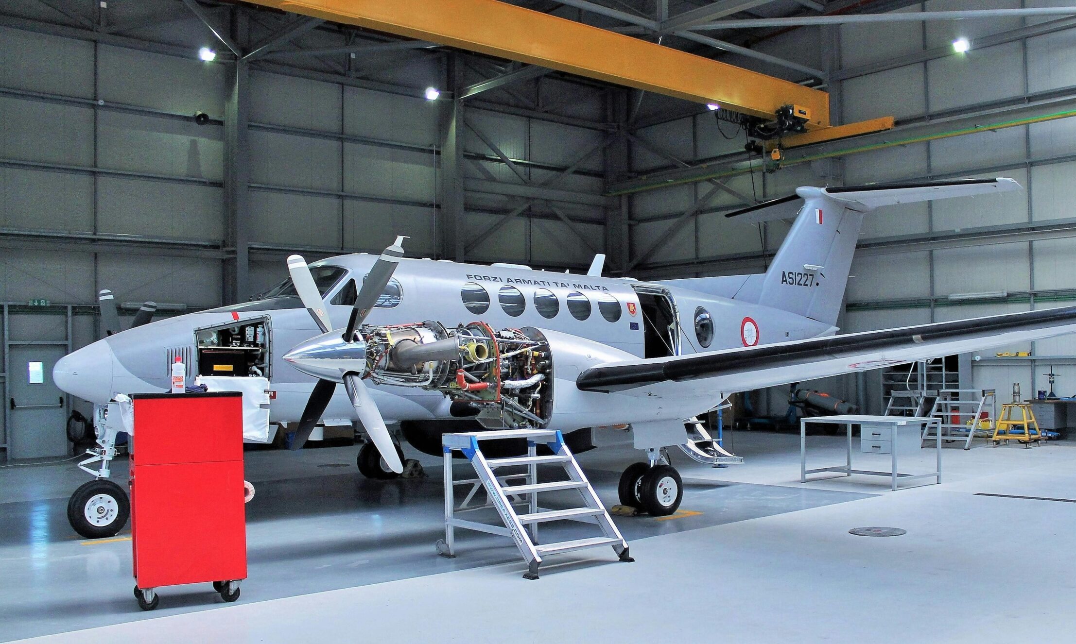 Aircraft undergoing maintenance in a spacious modern hangar.